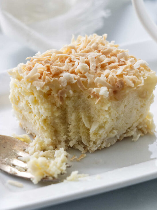 A fork cutting into coconut cheesecake bars.