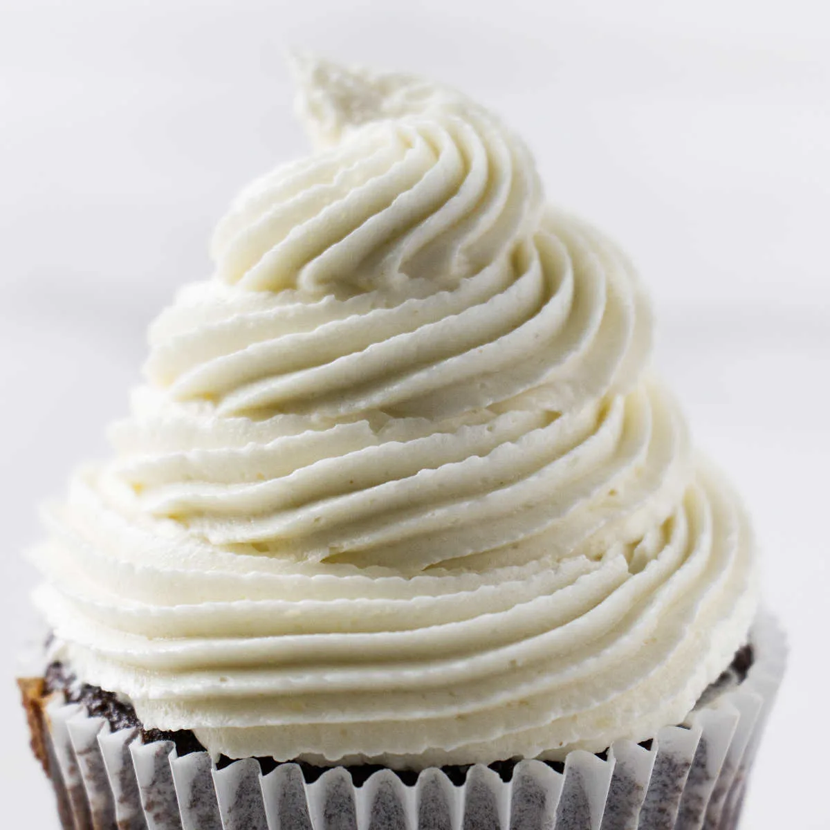A swirl of coconut buttercream ermine frosting on a cupcakes.