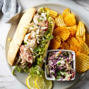 A shrimp and crab po boy on a plate with coleslaw.