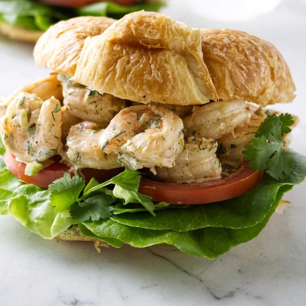 A shrimp salad sandwich on a croissant.