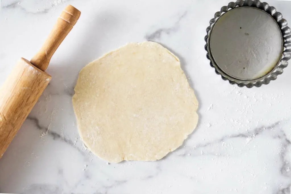 Rolling pie dough for a mini tart pan.