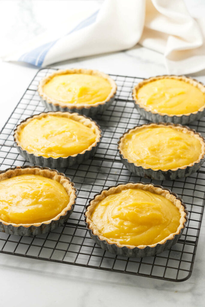 Adding lemon filling to mini tarts.