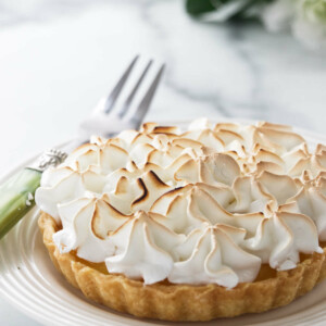 A mini lemon meringue tart on a plate.