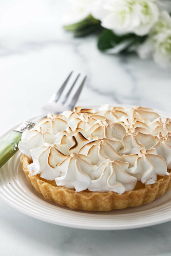 A mini lemon meringue tart on a plate.