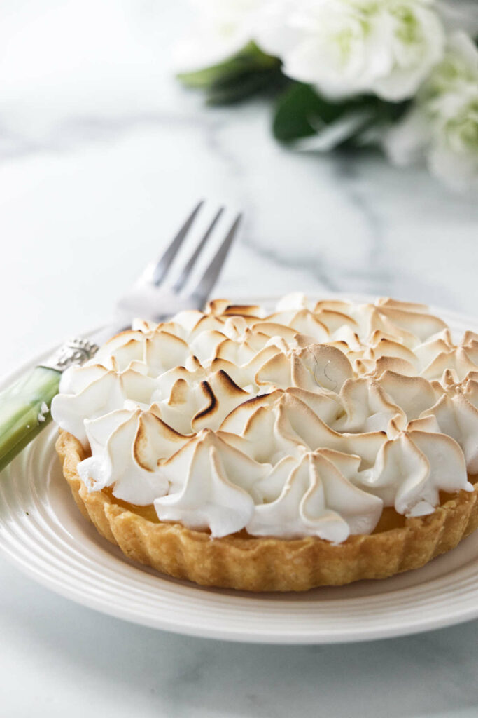 A mini lemon meringue tart on a plate.