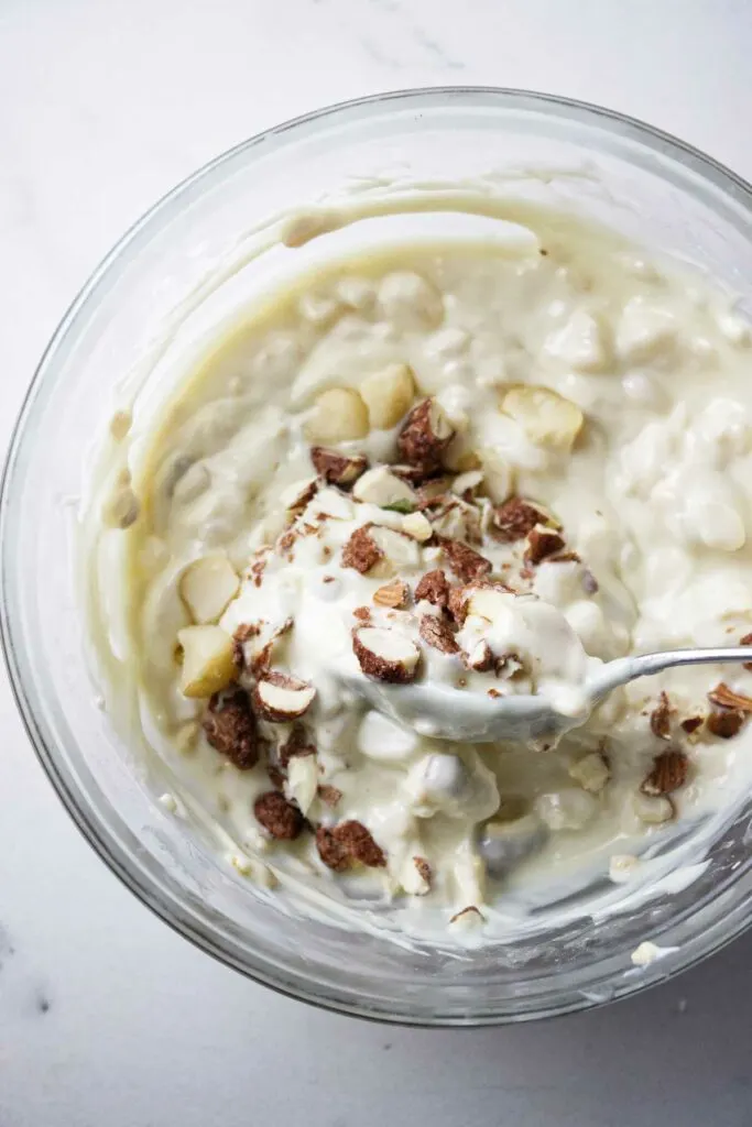 Adding nuts to a dish of melted white chocolate.