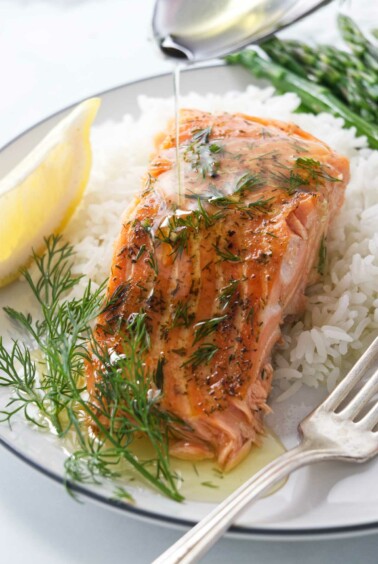 Drizzling butter over a cedar plank baked trout.