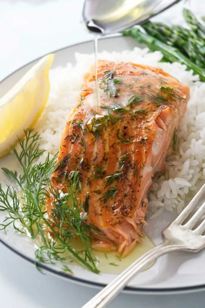 Drizzling butter over a cedar plank baked trout.