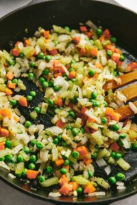 Adding the vegetables to the skillet.