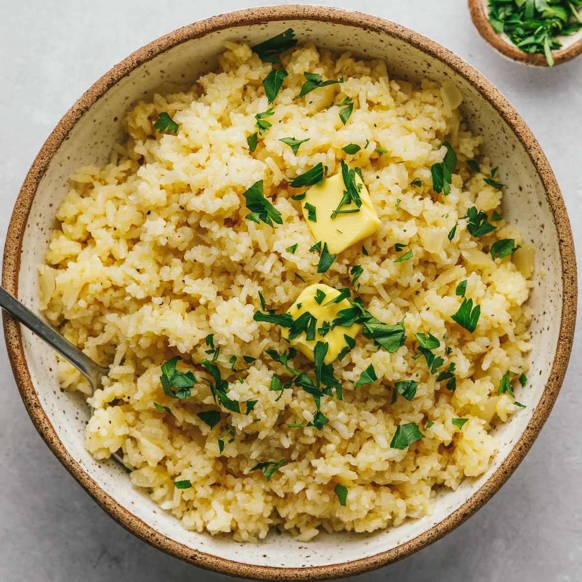 A bowl of garlic butter rice topped with fresh herbs.