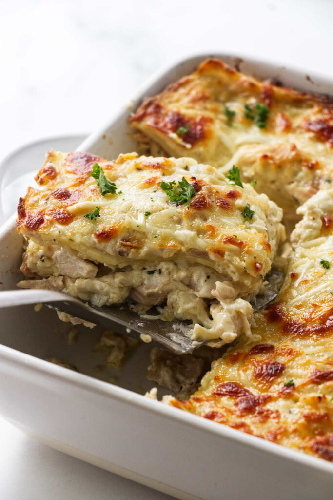 A slice of chicken lasagna in a casserole dish.