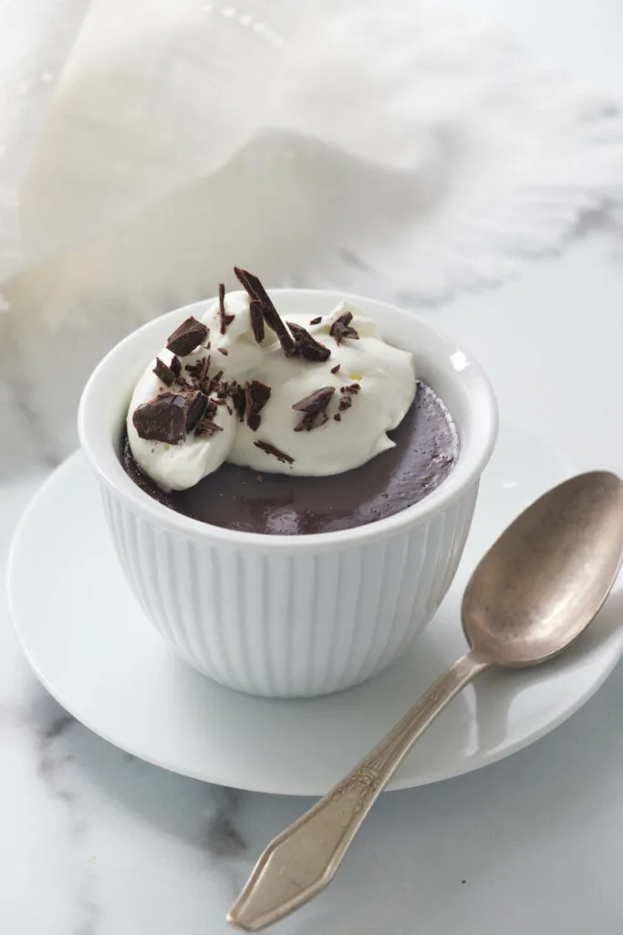 serving of chocolate pots de creme on a saucer with a teaspoon.