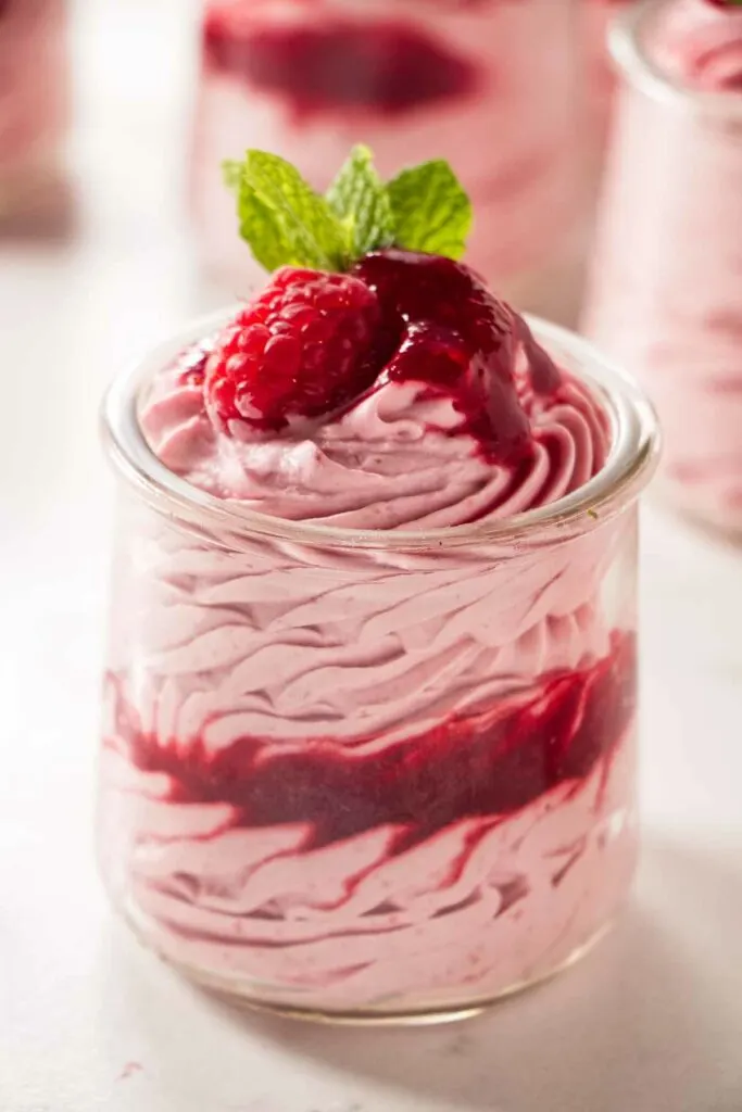 Raspberry mousse filling in a parfait cup with extra sauce swirled on top.