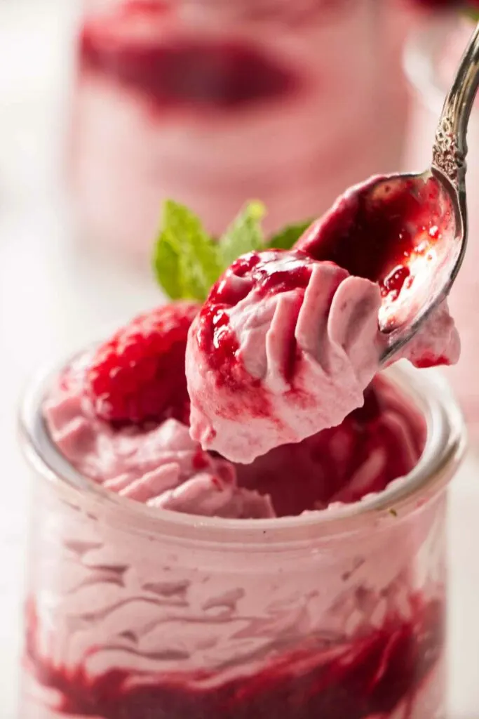 A spoon scooping out a bite of raspberry mousse cake filling.