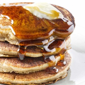 A stack of sprouted wheat pancakes with syrup and butter on top.