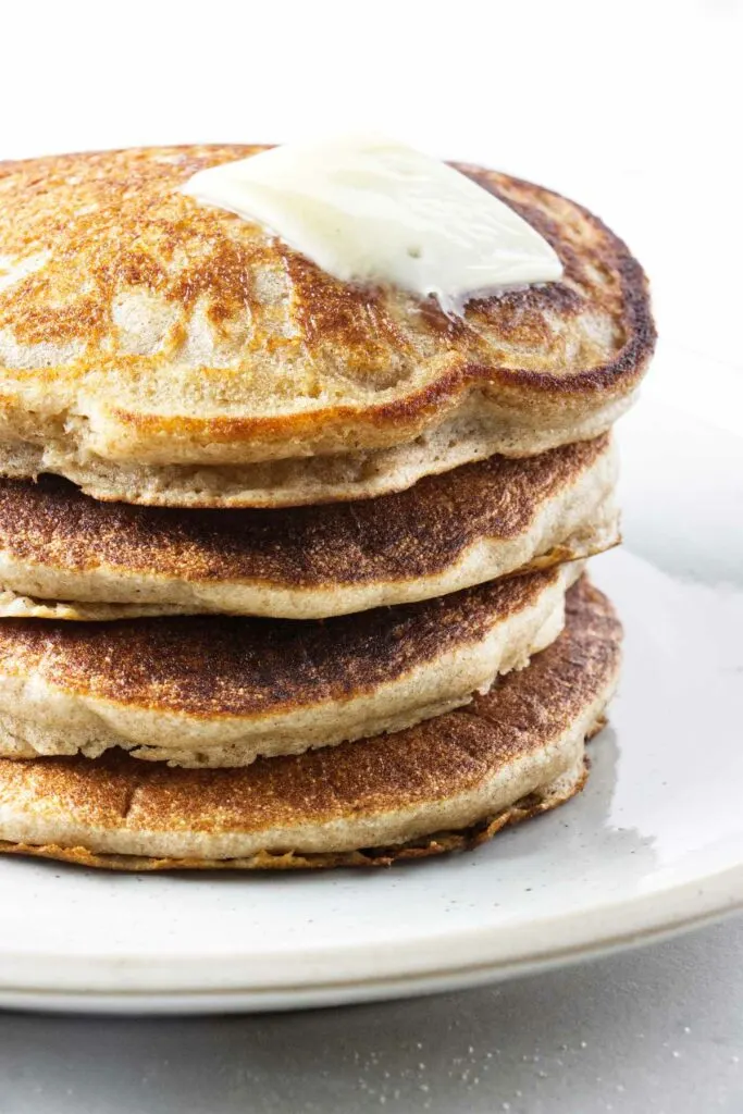 A stack of sprouted wheat pancakes with a pat of butter on top.