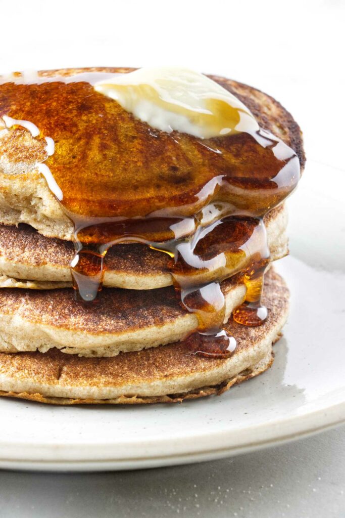 Syrup running down a stack of sprouted wheat pancakes.