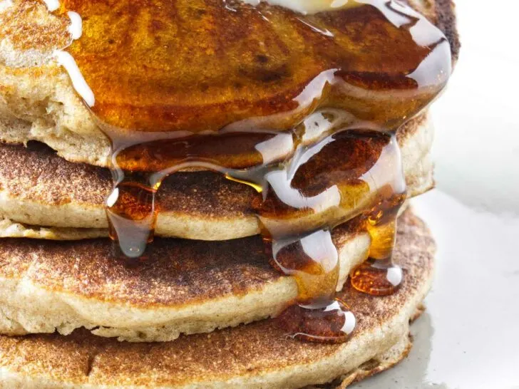 Syrup running down a stack of sprouted wheat pancakes.