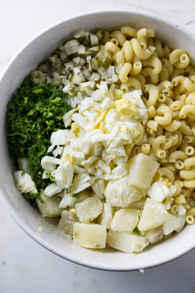 Ingredients for a Hawaiian potato salad in a large bowl.