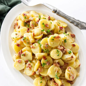 A serving platter filled with hot German potato salad.