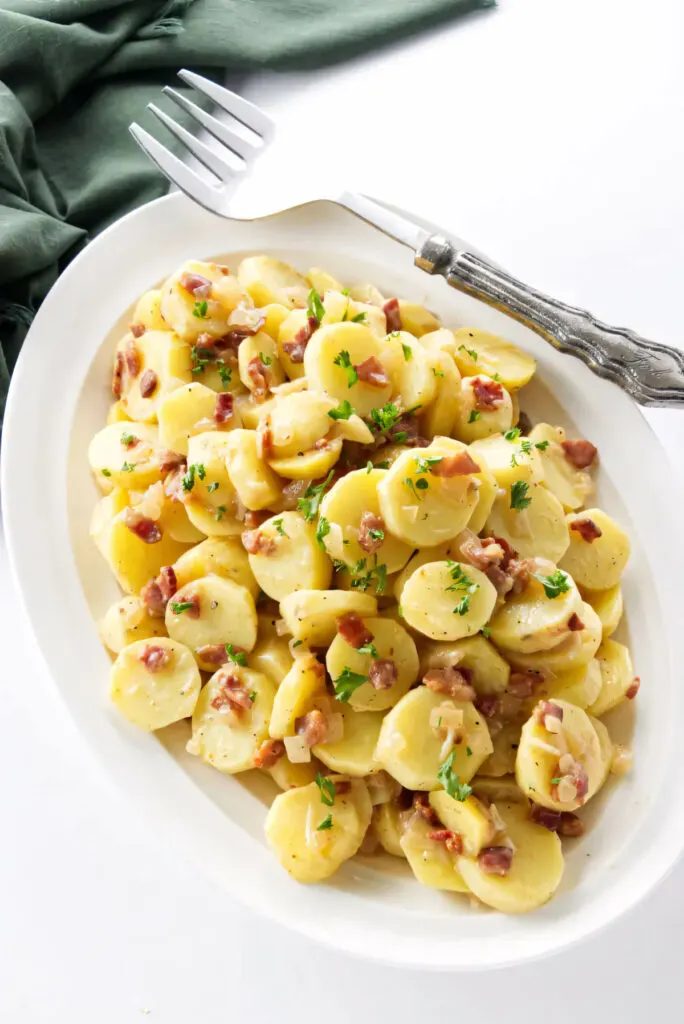 A serving platter filled with hot German potato salad.