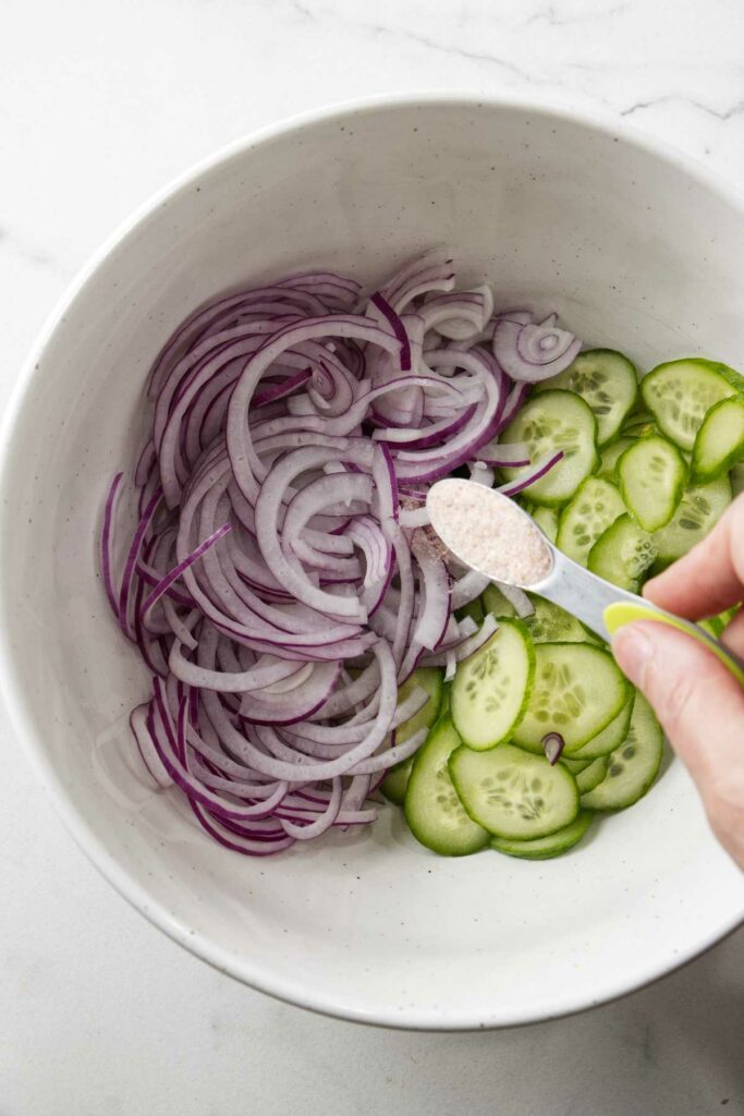 Salting the onions and cucumbers for an Asian potato salad.