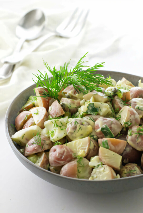 A serving bowl filled with baby red potato salad with creamy yogurt dressing.