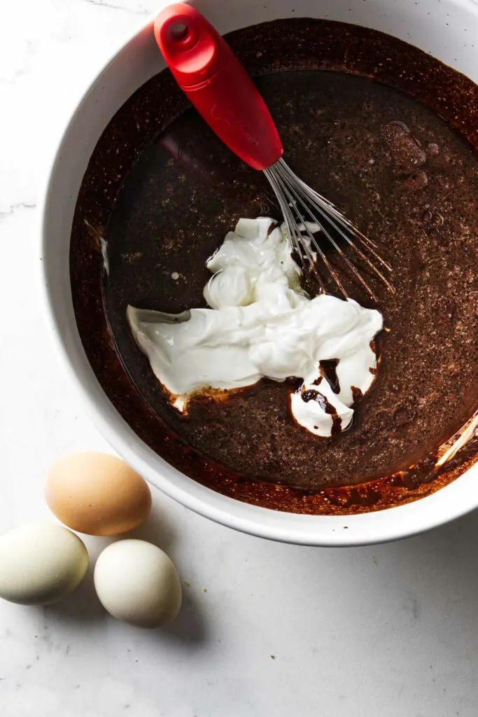 Mixing sour cream into chocolate cake batter.