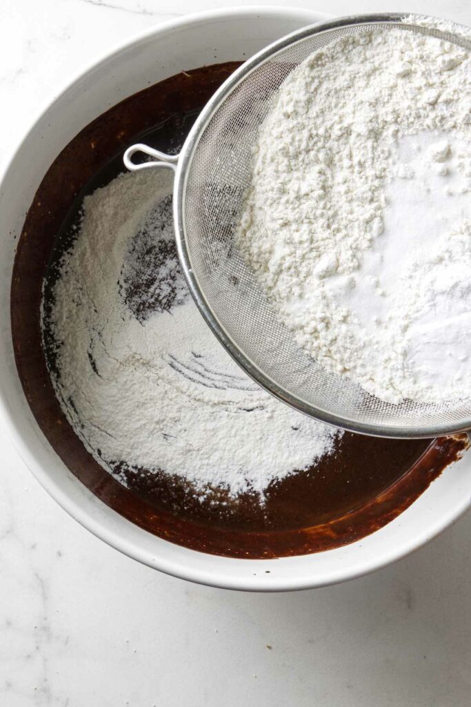 Adding flour to chocolate cake batter.