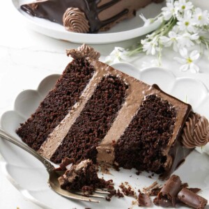A partially eaten slice of chocolate cake with chocolate buttercream.