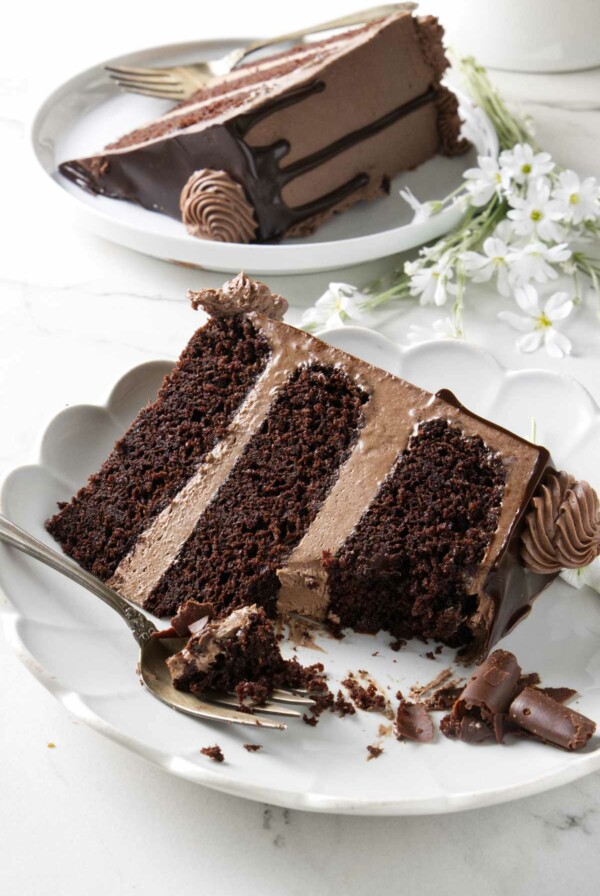 A partially eaten slice of chocolate cake with chocolate buttercream.