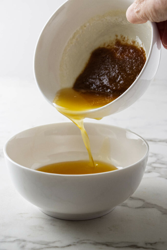 Pouring the clarified butter off the browned milk solids.