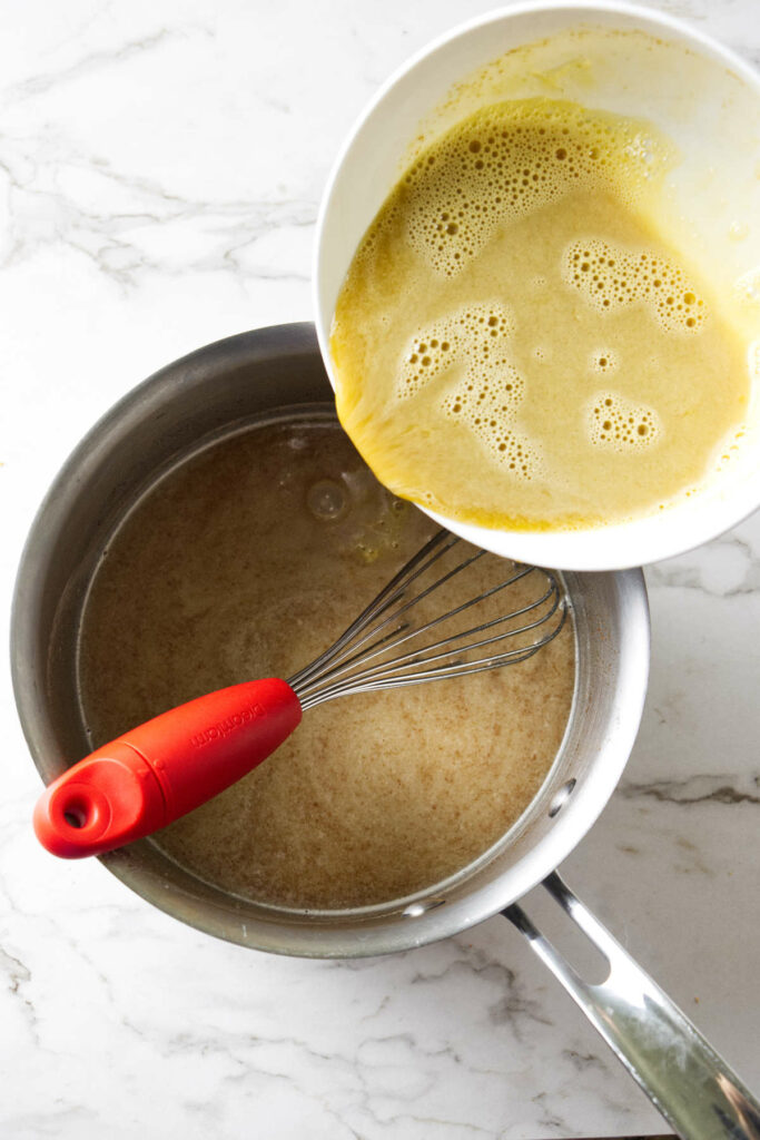 Pouring tempered egg yolks into brown butter ice cream mixture.