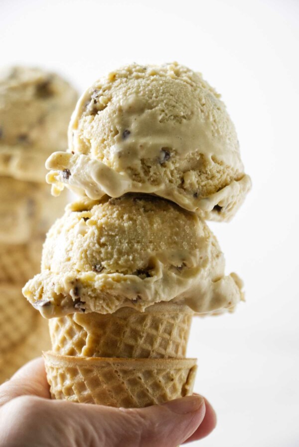 Two scoops of brown butter ice cream with toffee bits on a sugar cone.