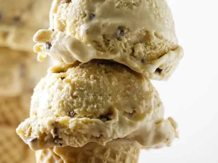 Two scoops of brown butter ice cream with toffee bits on a sugar cone.