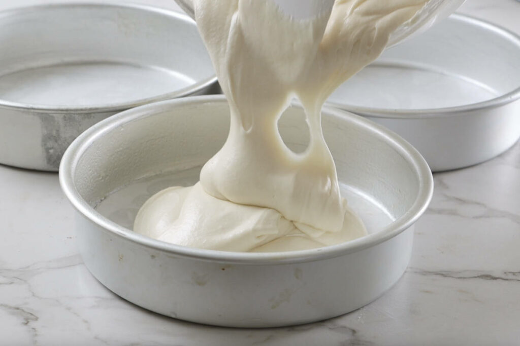 Pouring the cake batter into pans.