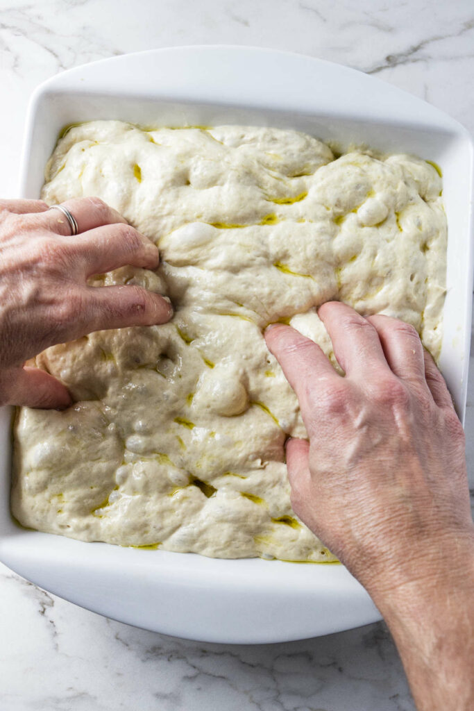 Pressing dimples in the top of white einkorn focaccia bread dough.