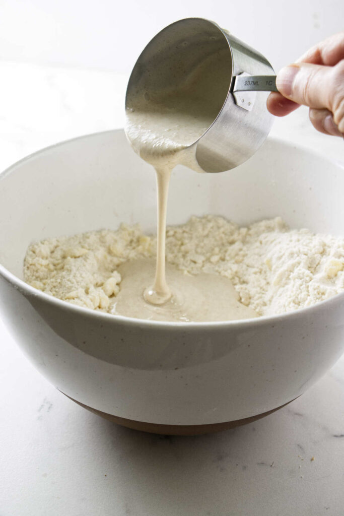 Pouring sourdough starter discard into pie dough pastry.