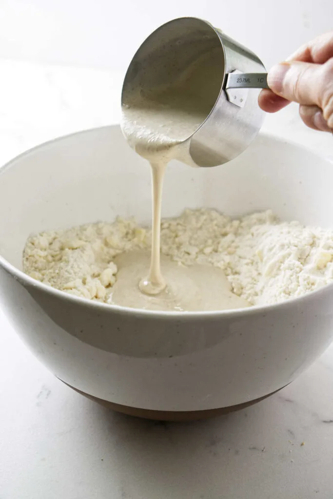 Pouring sourdough starter discard into pie dough pastry.