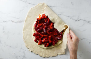 Folding pie crust over strawberry and cream cheese filling for a galette.