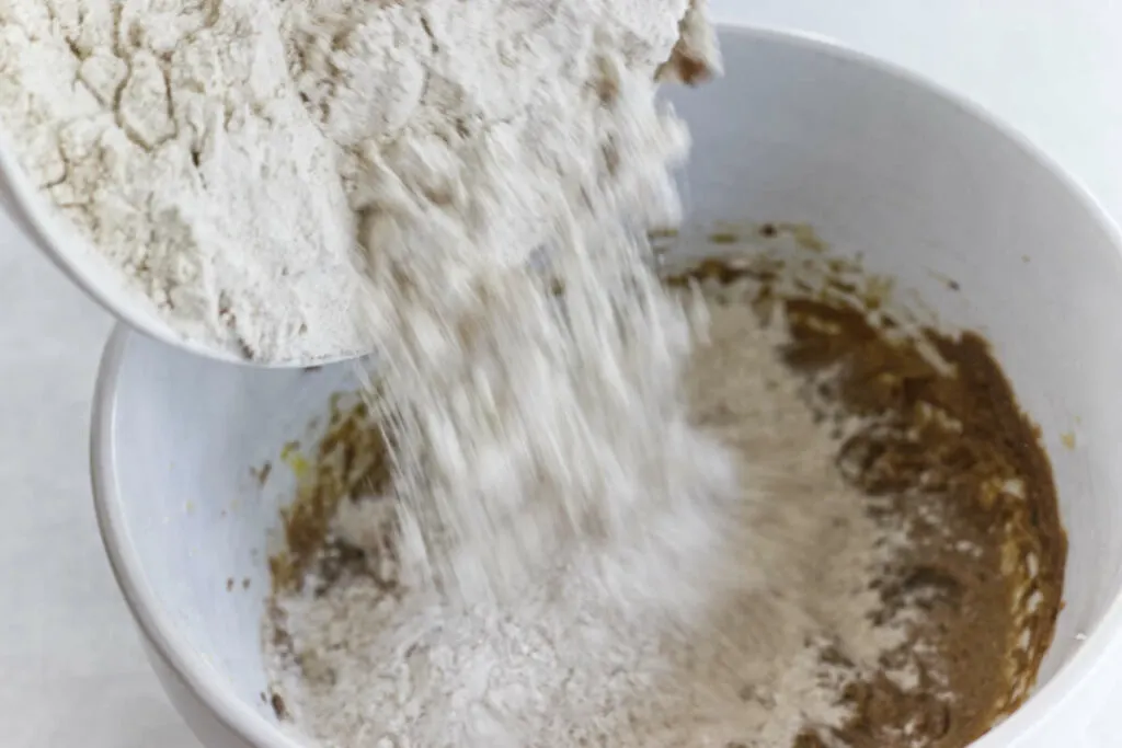 Adding flour to the mixing bowl.