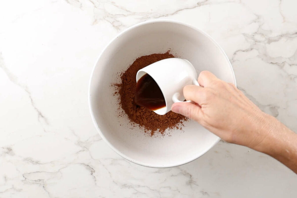 Adding hot liquid to cocoa powder.