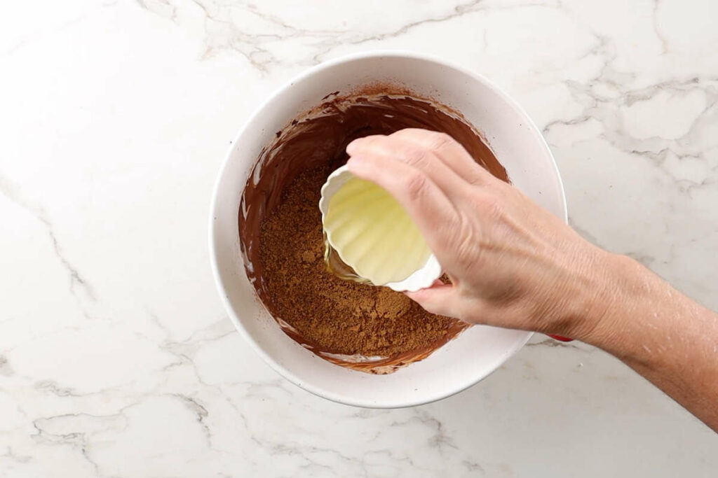 Adding sugar and oil to a bowl.