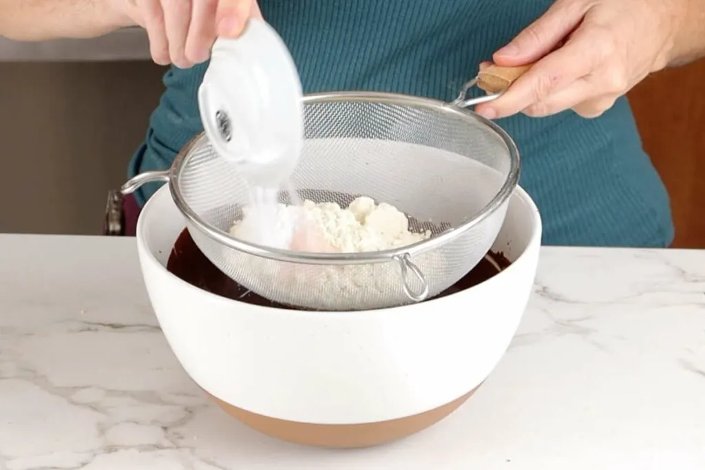 Sifting einkorn flour into cake batter.