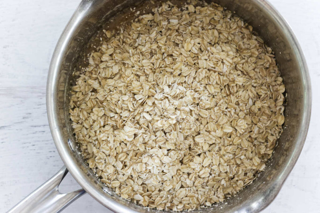 Adding oatmeal to a saucepan with the sugar to make no bake bars.