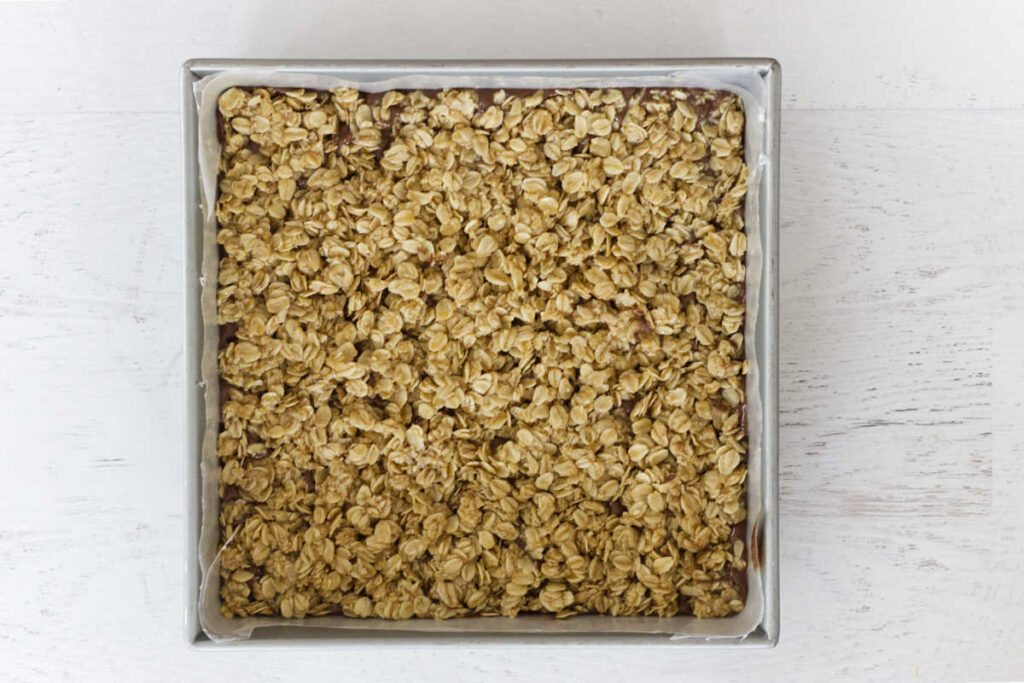 Spreading the granola mixture into a pan.