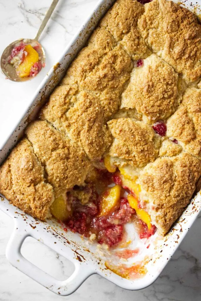 A 13 x 9 inch baking dish filled with a warm raspberry peach cobbler.