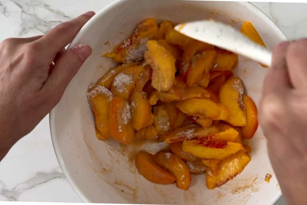 Mixing peaches with sugar to go on top of a coffee cake.