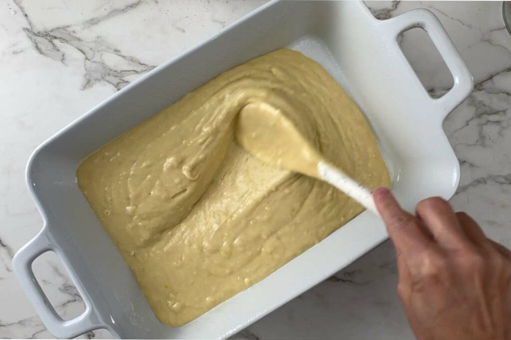 Spreading cake batter into a baking dish.