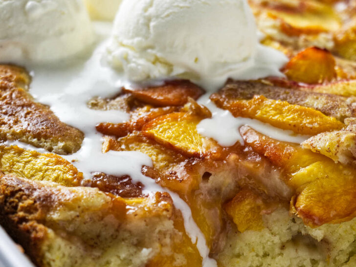 A peach coffee cake in a baking dish with 3 scoops of ice cream on top.